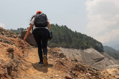 Bavulu ve şapkası olan genç bir kadın tatilde Rocky Dağı 'nda bir gölün kenarında yürüyor.