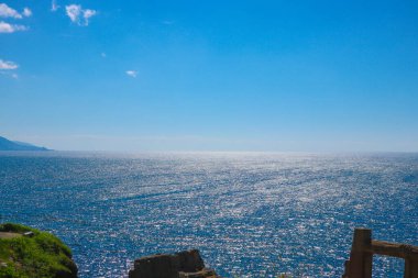 Manzara berrak bir gökyüzünün altında pırıl pırıl mavi bir okyanus..