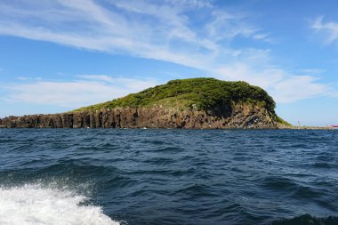 Sahne dramatik uçurumlar ve yemyeşil bitki örtüsüyle dolu pitoresk bir ada..