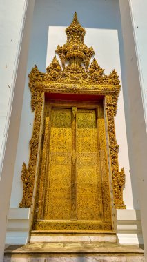Bangkok, Tayland, 11 Kasım 2024, bir tapınağın girişinde dik duran, karmaşık oymalarla süslenmiş altın kapı..