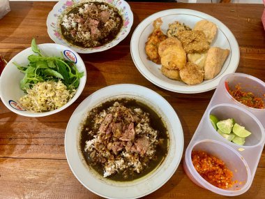 Rawon: A Savory Black Beef Soup from East Java, Indonesia. Complete with Vegetables, Sambal, and Fried Fritters.