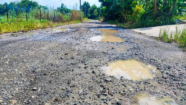 Tamir edilmesi gereken eski asfalt dokusu. Yol çukur ve deliklerle dolu. Çukur yolu - hasarlı kırsal yol yüzeyi 