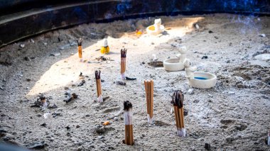  Tütsü, dua etmek için kum tütsüsü yakar. Tütsü çubukları arka planda dumanla yanıyor..