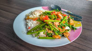 Kızarmış Morning Glory yanında kızarmış domuz eti ya da Tayland usulü kızarmış yumurta ile ahşap masada pilav. Tayland tarzı yemek..