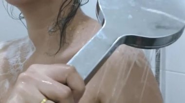 Duş alan bir kadın, güzel bir kız duş alıp eğleniyor, ellerini ve omuzlarını kapatıyor.