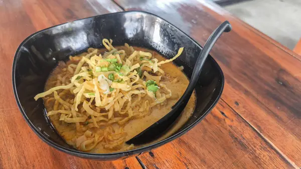 Khao Soi, Khao Soi Kai, Thai Noodles Khao Soi, ahşap zeminde baharatlı körili tavuk, Kuzey Tayland yemeği konsepti. (Lanna yemeği)