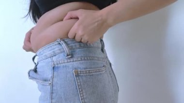 Kilolu bir kadın karnını sıkıyor ve aşırı kilolu olduğu için kendini kötü hissediyor..