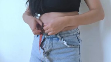 Kilolu bir kadın karnını sıkıyor ve aşırı kilolu olduğu için kendini kötü hissediyor..