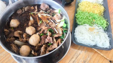 Haşlanmış domuz yahnisi, beyaz pirinç vermicelli ve yumurtalı erişte ayrı servis edilir.