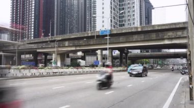 Bangkok 'ta trafik çok yoğun. Tayland 'da gündüz vakti yol kenarında reklam levhaları var. Arkasındaki manzara bir daire..