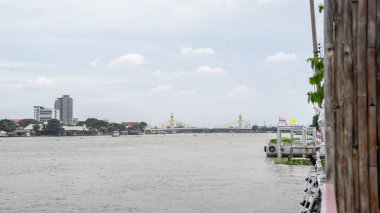 Banliyölerden akan büyük bir nehrin görüntüsü. Nehir kıyısının diğer tarafındaki bir kameradan çekilmiş. Diğer taraftaki yüksek binaların inşaatının başlangıcını gösteriyor. 