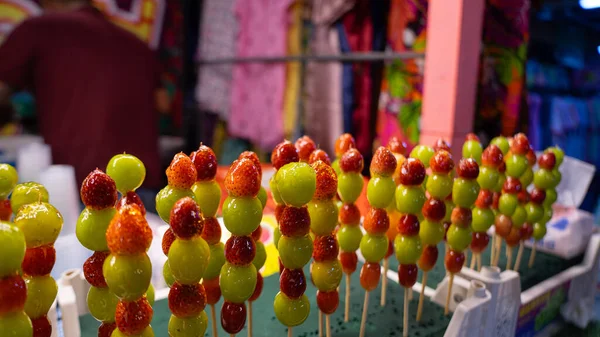 Pictures of sweet street food menus at temple fairs This menu is fruit skewers. It consists of large green grapes. and small strawberries skewered and drizzled with syrup.