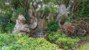 Bulunduğu yerin fotoğrafları, Stone Waterfall Garden 'ın, yüksek ağaçlar ve çeşitli yeşil çalılarla dolu huzurlu bir doğal atmosferde çekilmesi. Büyük kayalar çok katmanlı küçük bir şelalenin etrafına dizilir.. 