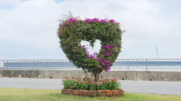 artificial tree Planting heart-shaped flowers in the ground Using a structure made from wire And the area around the base has additional decorations. Located on the edge of the park Along the reservoi