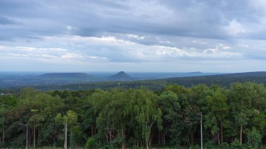 Uzak manzaranın atmosferi, yüksek açılı bir manzara, ormanı ve bereketli dağları gören. Koyu tonlu bir gökyüzü vardı. Üç boyutlu görünen yoğun bulutlar vardı. Güneş parlıyordu.