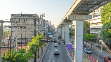 23 Aralık 2023 'te Bangkok, Tayland şehir sokaklarında, Tayland yollarında merkez ada yapım aşamasındaki yüksek bir üstgeçittir. Yolun kenarı binalarla dolu. Elektrik direkleri, dağınık kablolar., 