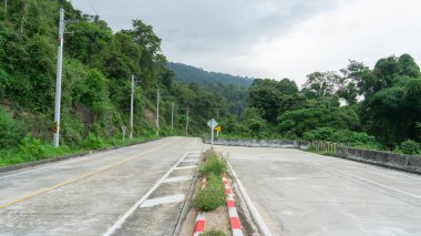Yol dağa çıkıyor. Yolun kenarları sık orman ağaçlarıyla çevrilidir. Yolu kapatan küçük bir merkez ada var. Yol boyunca elektrik direkleri var.