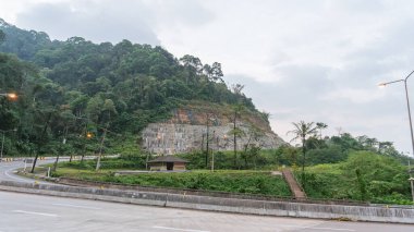 Çeşitli yeşil ağaçların doğal atmosferindeki küçük binaların turist çekimleri. Aşağı inen ahşap bir merdiven var. Tehlikeli bir virajın yanında yol boyunca büyük bir viraj var.
