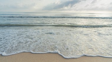 Köpüklü dalgaların temiz beyaz bir kumsal sahiline çarpması. Hiçbir çöp ya da israf yok. Bu plaj bölgesinde. Denize doğru yavaşça kıyıya doğru sürükleniyor. 