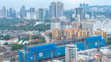 Havadan bakıldığında şehrin göbeğine yeni bir bina inşa edildiği görülüyor. Gökdelenler dizilmişti. İnşaat halindeki binanın her tarafında mavi bir branda vardı..
