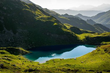 Grand Arc 'ta yaz, Maurienne, Fransız Alpleri. Bu manzara, Fransız Alpleri 'nin Maurienne bölgesindeki Büyük Yay' ın içine yerleşmiş sakin bir dağ gölünün nefes kesici güzelliğini yansıtıyor..