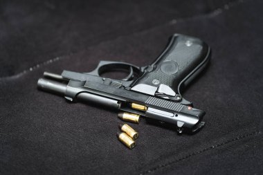 Compact pistol for self-defense and cartridges on a black sofa, close-up photo. High quality photo