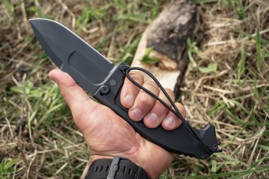 Large heavy folding camp knife in male hand, close-up photo. High quality photo