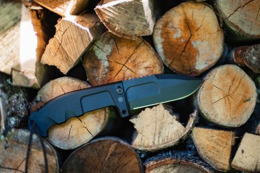 Folding heavy expedition knife and firewood in nature, close-up photo. High quality photo