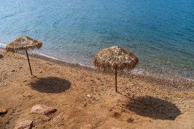 Wild beach with umbrellas near Athens. Close up. 