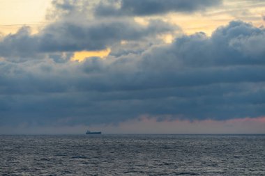 Seascape in the Baltic Sea at sunset. A cargo ship at sea, the sky is overcast. High quality photo