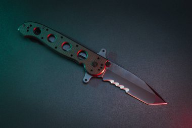 Folding tactical knife with serrated sharpening, close-up photo. High quality photo