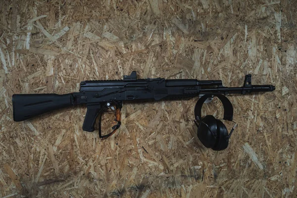 Kalashnikov AK 74m assault rifle in a shooting range on the wall and safety glasses and headphones. High quality photo
