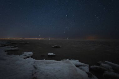 Peyzaj astrofotoğrafçılığı. Baltık Denizi 'nin buzlu kıyısı ve yıldızlı gökyüzü. Yüksek kalite fotoğraf