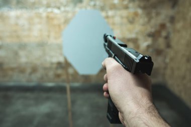 Bir adamın elindeki tabanca atış poligonundaki kağıt hedefe nişan alınır. Yüksek kalite fotoğraf