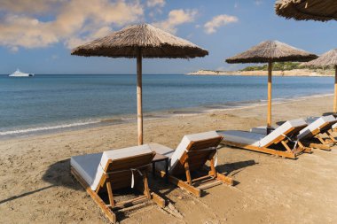 Yunanistan 'ın Atina kentindeki kumlu bir plajda palmiye şemsiyeli güneşlikler. 