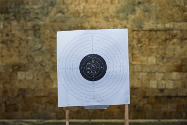 A shooting target with bullet holes in a shooting range in front of a bullet catcher.  clipart