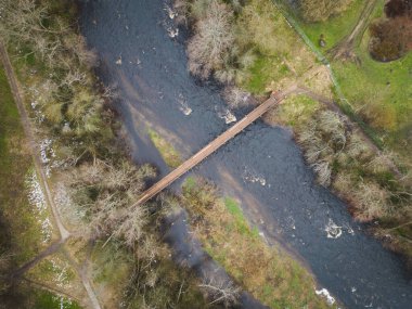 Pirita Kose bölgesinden botanik bahçesine giden nehir üzerinde bir köprü. Hava bulutluyken, bir bahar gününde bir drondan fotoğraf.. 