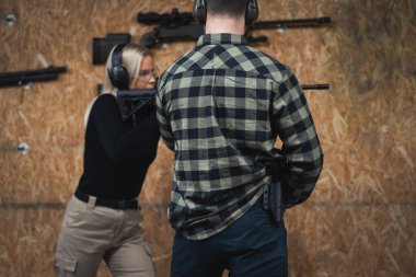 Genç bir kız atış poligonunda bir eğitmenle taktik tüfek kullanmayı öğreniyor.. 