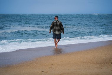 Genç bir çift, bahar günü dalgalar sırasında Nazar sahillerinde yürür..