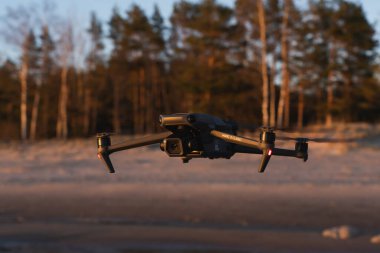 Estonya, Tallinn 16 Mayıs 2024. Drone dji mavic 3 klasiği gün batımında veya şafakta deniz sahilinde uçuyor.. 