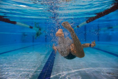 Su altı fotoğrafı, bir kız su altında spor havuzunda yüzüyor, dikiz manzaralı.. 