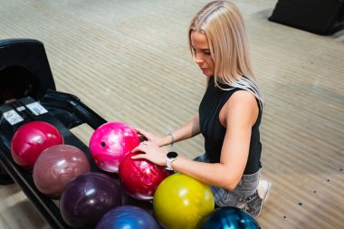 Sarışın bir kız bowling topu alıyor, yakın plan bir fotoğraf.. 