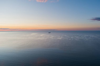 Gün batımından sonraki sakin bir yaz akşamında Baltık Denizi 'nde bir konteyner gemisi ufukta beliriyor. Drone görünümü. 