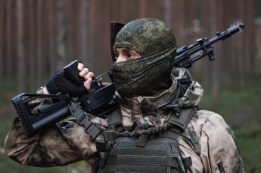 Ormanda elinde AK 12 tüfeğiyle kar maskeli ve kamuflajlı bir asker.. 