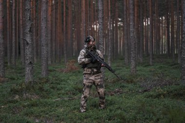 Kafasında gece görüşü cihazı ve elinde AK-12 tüfeğiyle gece karanlığında ormanda kamuflajlı bir asker.. 