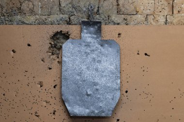 Atış poligonunda siluet şeklindeki metal bir hedef bir kurşun tutucuya, yakın çekim fotoğrafına tutunur.. 