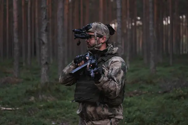 Kafasında gece görüşü cihazı ve elinde AK-12 tüfeğiyle gece karanlığında ormanda kamuflajlı bir asker.. 