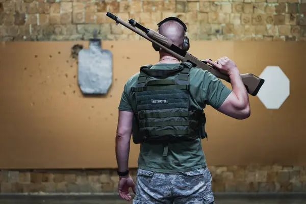 Atış poligonunda elinde tüfekle atış talimi yapan bir erkek eğitmen.. 