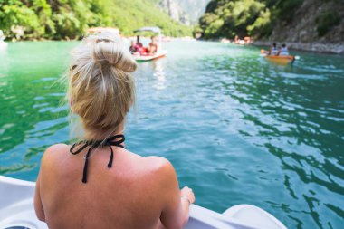 Bir yaz günü Fransa 'nın güneyinde Verdon Gölü' nde bir teknede sarışın bir kız. Arkadan bak..