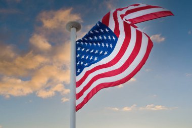 Amerikan bayrağı günbatımına karşı rüzgarda dalgalanıyor..